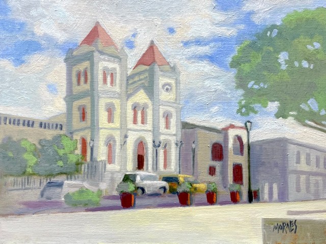Pintura de una iglesia con torres de techo rojo, rodeada de árboles y edificios, en un paisaje urbano claro y soleado.