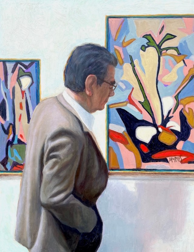 Un hombre de mediana edad contemplando obras de arte en una galería. Lleva un traje claro y está de perfil, observando dos pinturas abstractas en la pared.