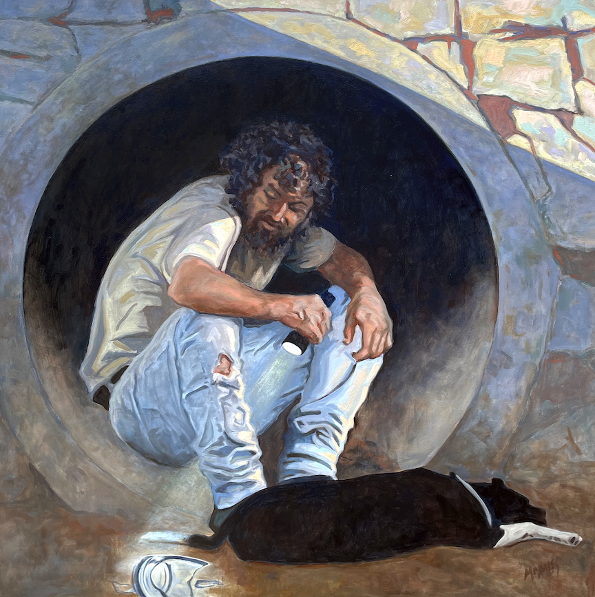 Hombre sentado dentro de un tubo de concreto, con cabello rizado y barba, vistiendo una camiseta blanca y pantalones rasgados. A su lado, hay un perro negro acostado. La escena muestra un ambiente urbano y un contraste entre la tristeza y la calma.