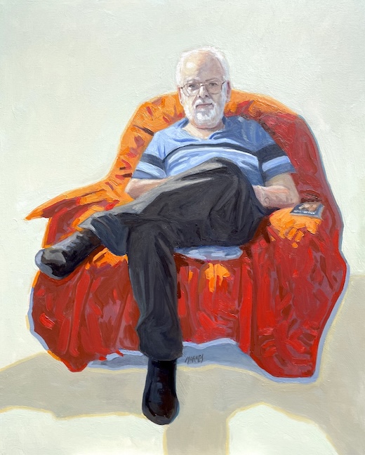 Retrato de un hombre de edad avanzada sentado en un sillón rojo, vestido con una camiseta de rayas y pantalones oscuros, con una expresión pensativa.