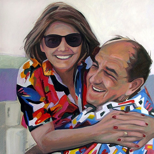 Retrato de una pareja sonriente, una mujer con gafas de sol y una camiseta colorida abrazando a un hombre que también lleva una prenda colorida. La expresión de ambos refleja alegría en un ambiente informal.